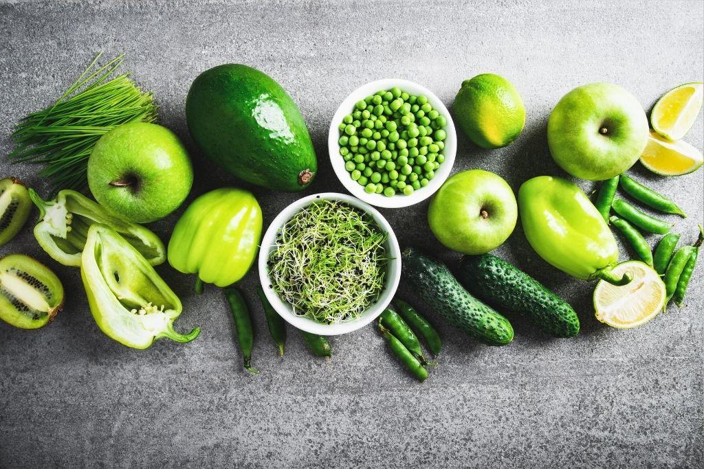 Vihreitä vihanneksia ja hedelmiä pöydällä.
