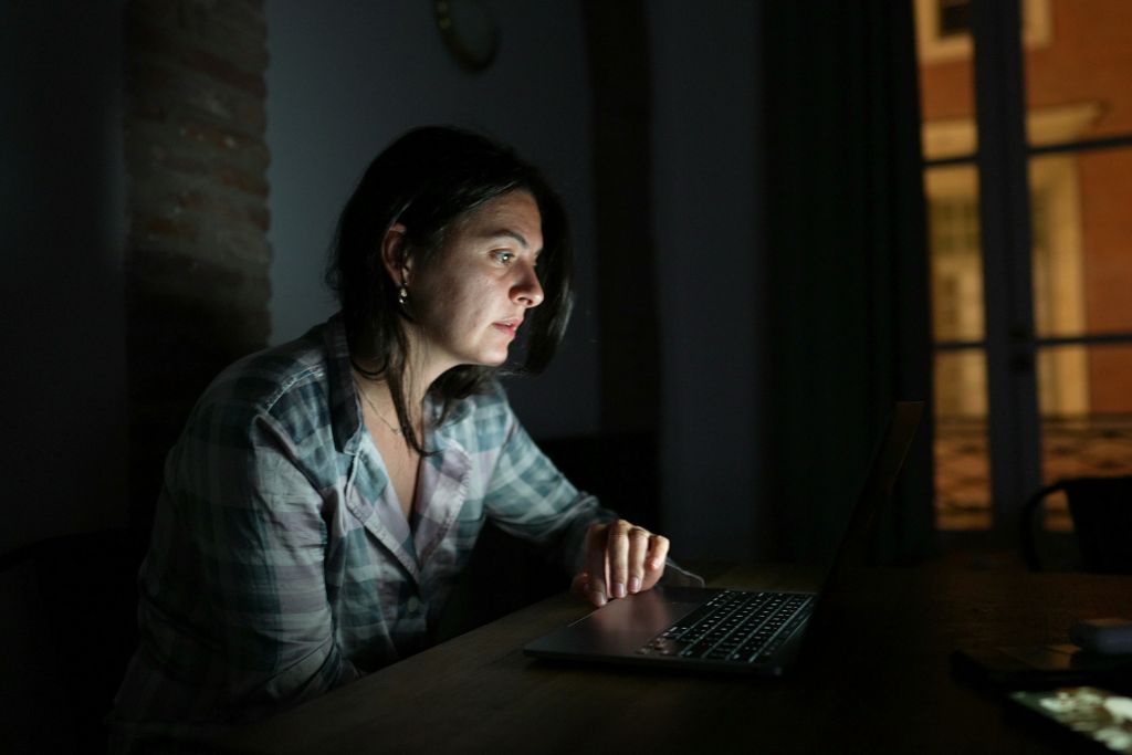 Nainen valvoo tietokoneen äärellä.